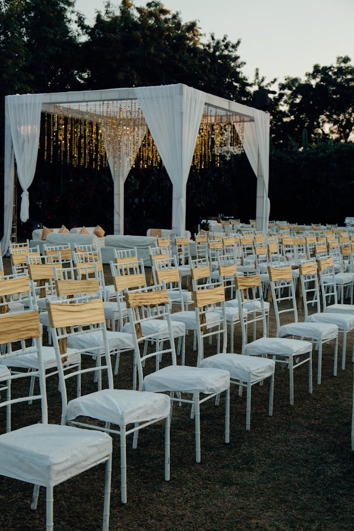 Charming outdoor wedding venue with white chairs and altar under evening sky.